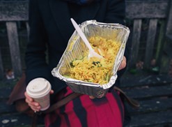 Woman holding coffee and a takeout order of fried rice