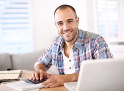 Man smiling as he checks on his online savings account from his computer at home.